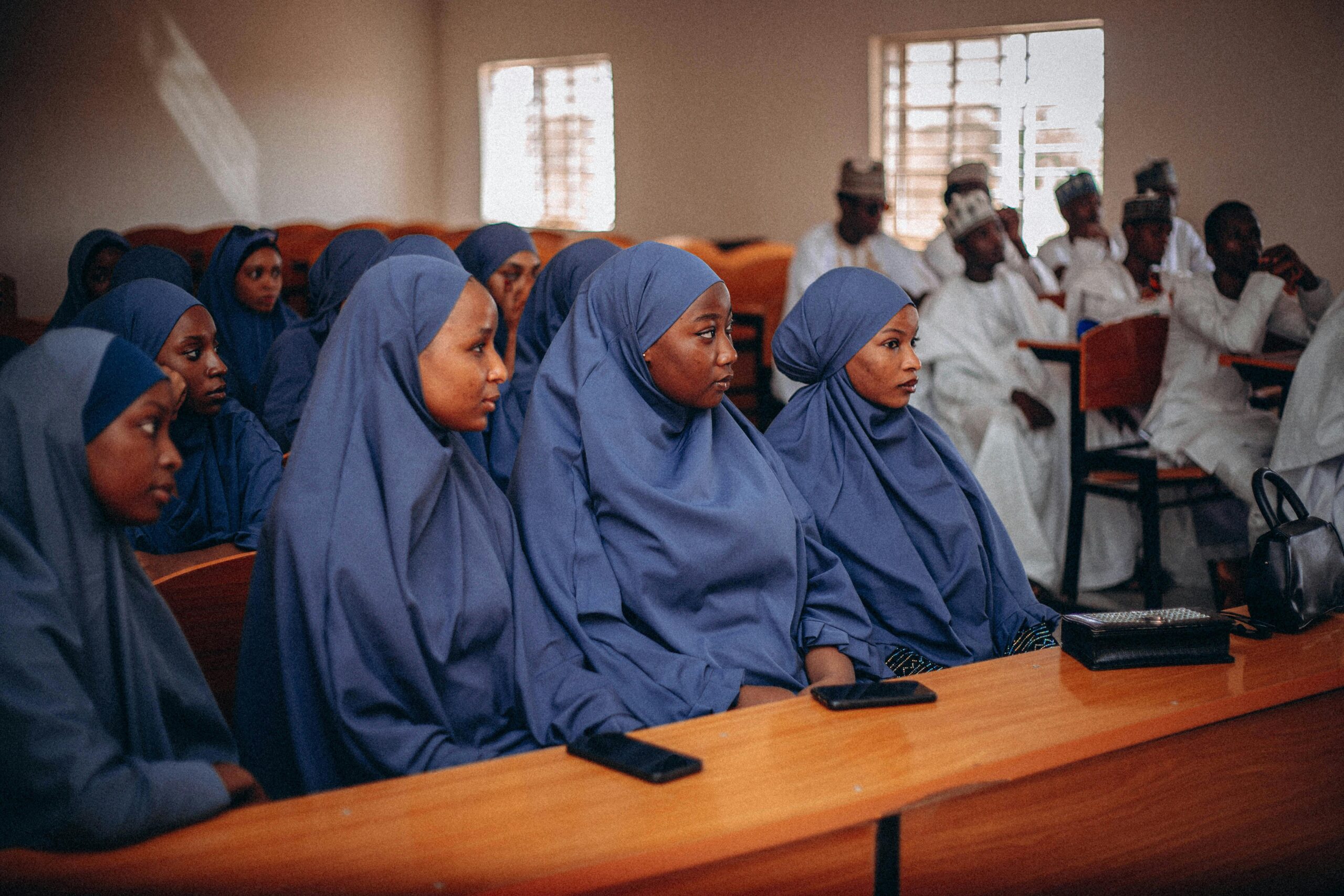 Studentinnen mit Hijabs besuchen mit aufmerksamen Mienen eine Vorlesung in einem Klassenzimmer.
